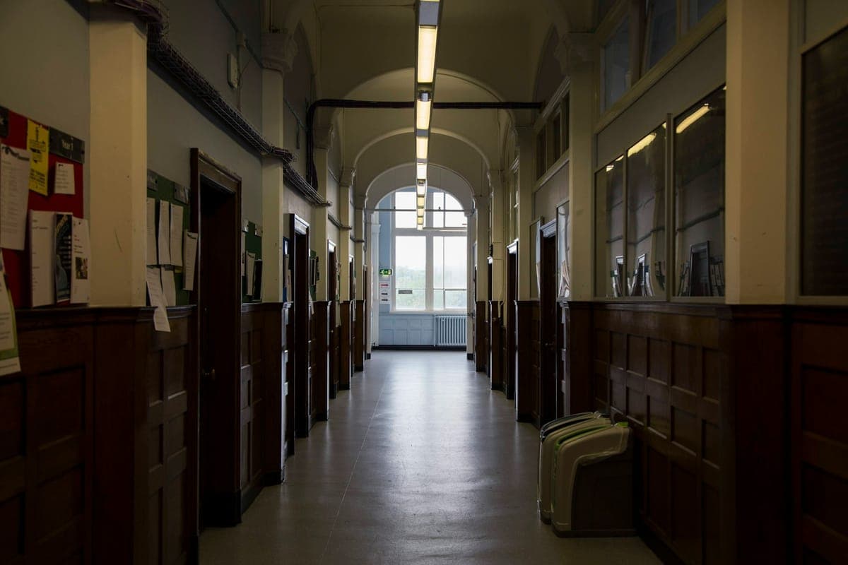 A school corridor with wood panelling and an arched window